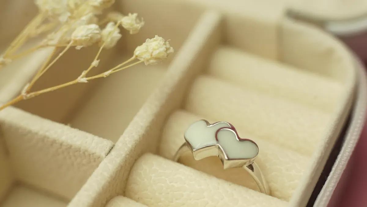 Anillo de dos corazones de leche materna en un joyero de terciopelo crema