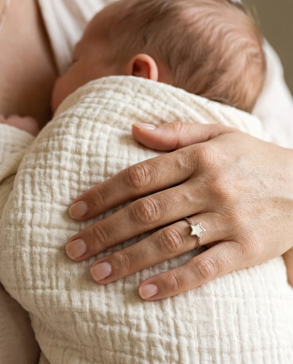 Mano con un anillo de estrella de leche materna sobre la espalda de un bebé