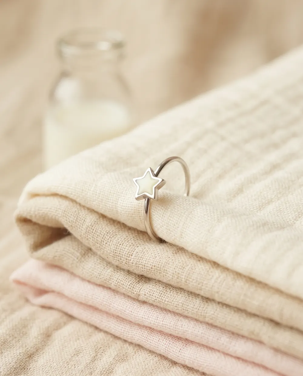 Anillo de plata con estrella de leche materna sobre una muselina de bebé