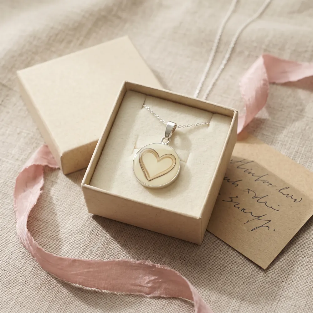 Colgante de leche materna en una caja de regalo con lazo rosa