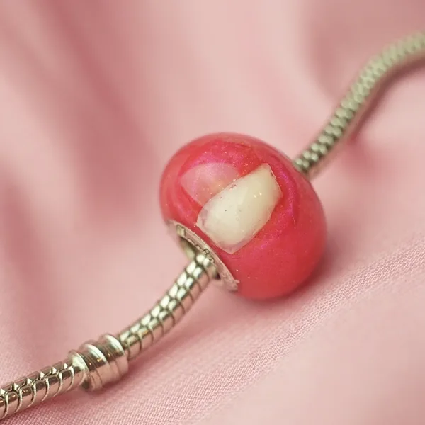 Charm rosa con un diente de leche dentro