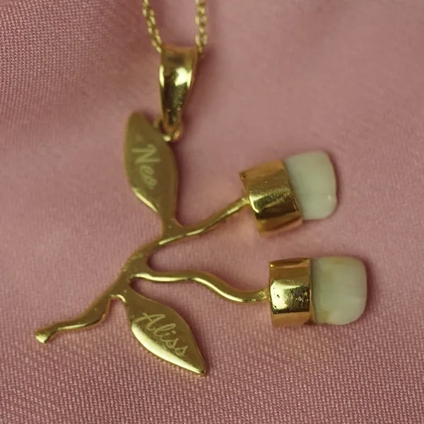Colgante rama con dos dientes de leche y baño de oro