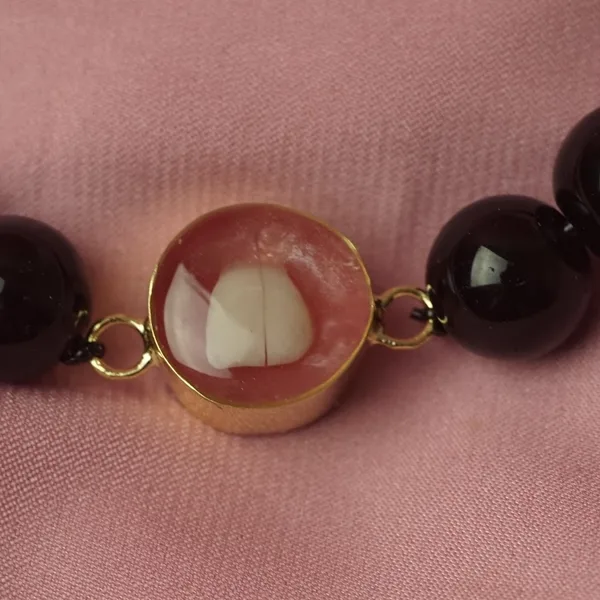Pulsera con un diente de leche en resina rosa