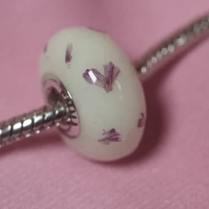 Charm de leche materna con pétalos de flores secas en una pulsera de plata