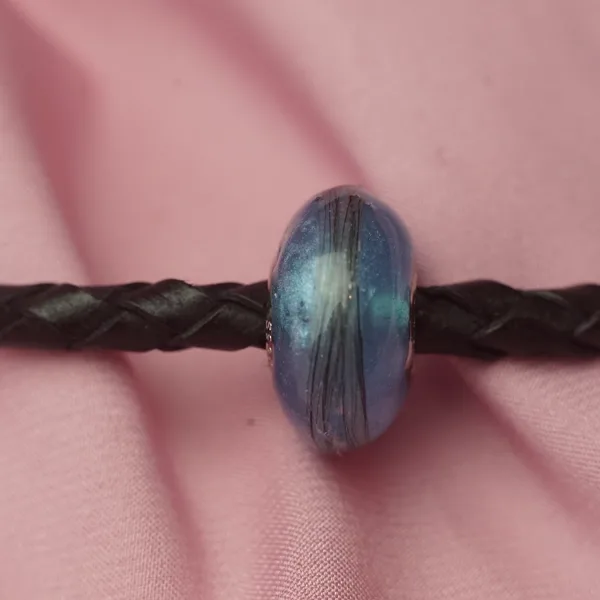 Charm azul con hebras de pelo en cordón de cuero