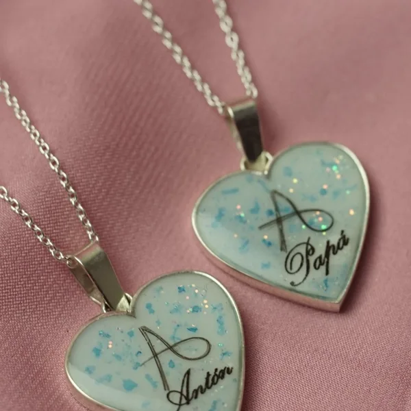 Dos colgantes corazón con iniciales y nombres hechos con pelo